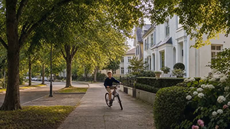 imoo spot: a boy rides his bike down a tree-lined street